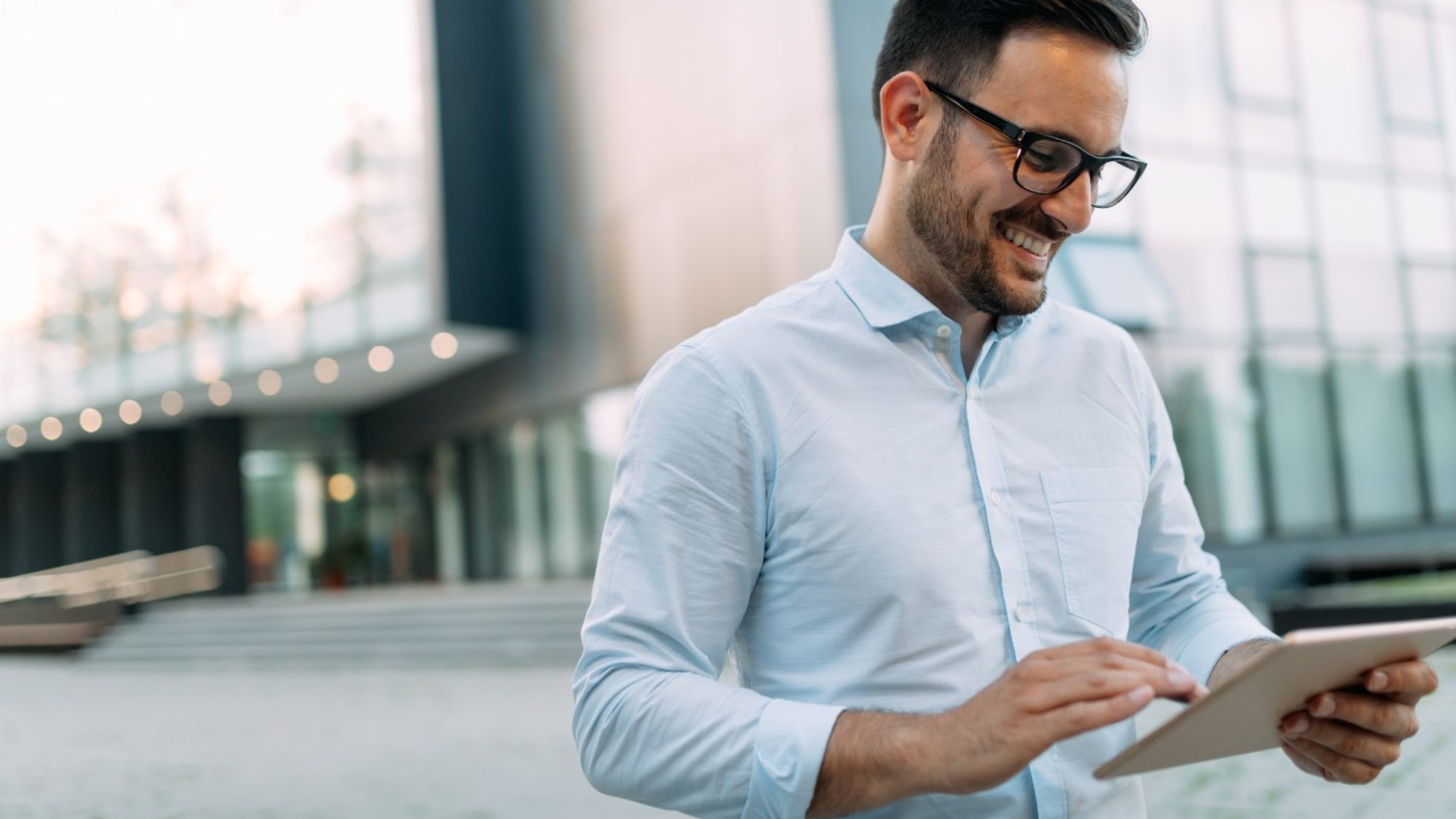 portrait-of-businessman-in-glasses-holding-tablet-AWVHCJU-2000x1125